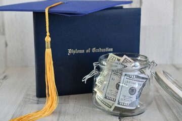 Graduation cap mortarboard tassel on diploma by a jar of money cash, concept school loans debt education costs