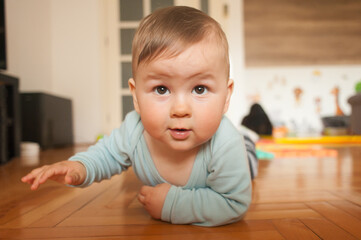 Cute baby boy crawls on the home floor, explore the world and learn to move. Love and family emotion