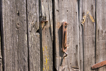 An old, original doorknob on a centuries-old wooden barn door in the harsh afternoon sun. Day. - 609412353