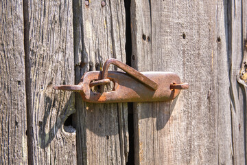 An old, original doorknob on a centuries-old wooden barn door in the harsh afternoon sun. Day. - 609412375