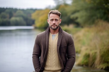 Portrait of a handsome young man standing by the river in autumn