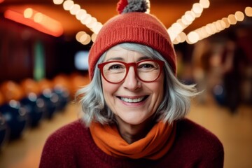 Fototapeta premium Portrait of smiling senior woman wearing red hat and scarf in cafe