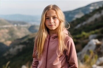Portrait of a beautiful little girl with blond hair on the background of mountains
