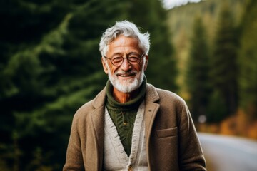 Portrait of a senior man with a gray beard and glasses in the mountains