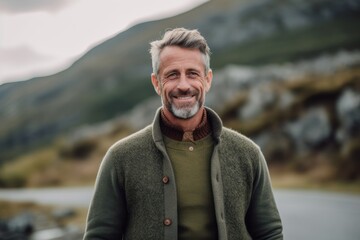 Portrait of a smiling senior man standing outdoors in the countryside.