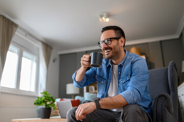 Low angle view of young businessman laughing cheerfully and having coffee while sitting on...