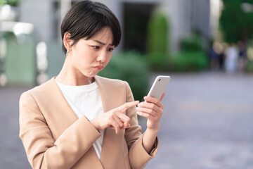 悩みながらスマートフォンを操作する女性