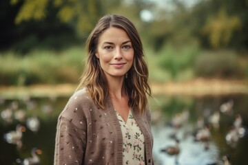 Naklejka premium Portrait of a beautiful young woman standing in the park with ducks