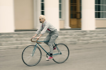 Adult hipster man rides on his retro fixed gear bicycle on moving blur background