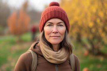 Portrait of a middle-aged woman in a hat and scarf in autumn park