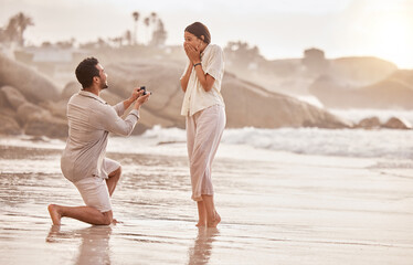 Couple at beach, surprise proposal and engagement with love and commitment with ocean and people outdoor. Travel, seaside and man propose marriage to woman, wow reaction and happiness with care - Powered by Adobe