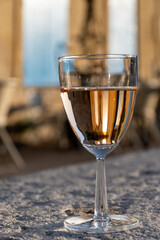 French rose dry wine from Provence in glass in sunny day with view on old streets of Arles town in...