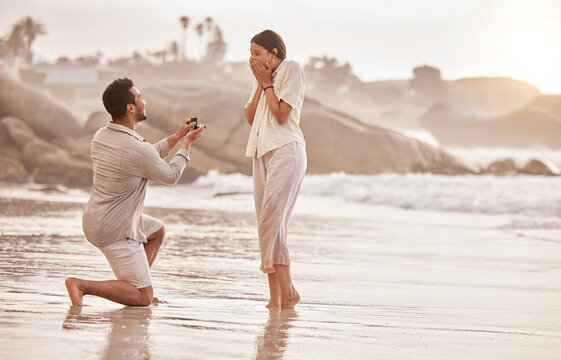 Couple at beach, surprise proposal and engagement with love and commitment with ocean and people outdoor. Travel, seaside and man propose marriage to woman, wow reaction and happiness with care