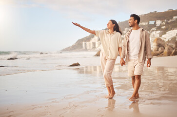 Mockup, pointing and a couple holding hands on the beach while walking together on a date for romance. Love, happy or smile with a man and woman taking a romantic walk by the coastal ocean or sea
