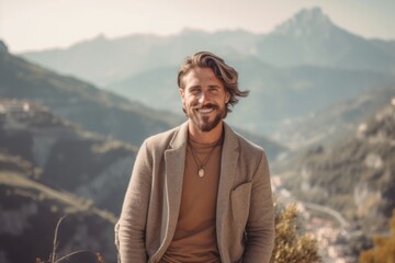 Fototapeta na wymiar Handsome young man in casual clothes standing on top of a mountain and smiling