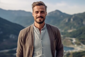 Portrait of a handsome young man standing on top of a mountain and smiling