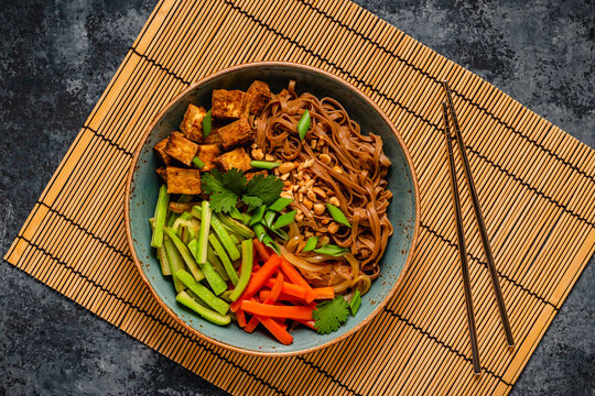Soba noodles with vegetables and fried tofu in a bowl.