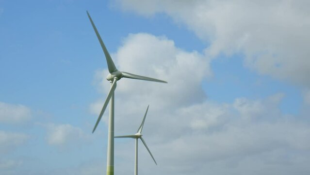 Two Wind Turbines against a blu summer sky with some clouds on a windy day in East Frisia, Lower Saxony, Germany. 2023