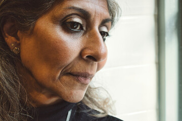 Close-up head-shot portrait of an attractive mature serious Indian woman looking pensive