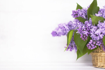 a bouquet of lilacs in a basket on a white background. a bouquet of lilac and a copy of the space. background with lilac flowers.