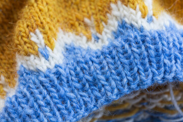 Yellow blue white wool yarn rib knitting close-up, traditional icelandic pattern macro photography