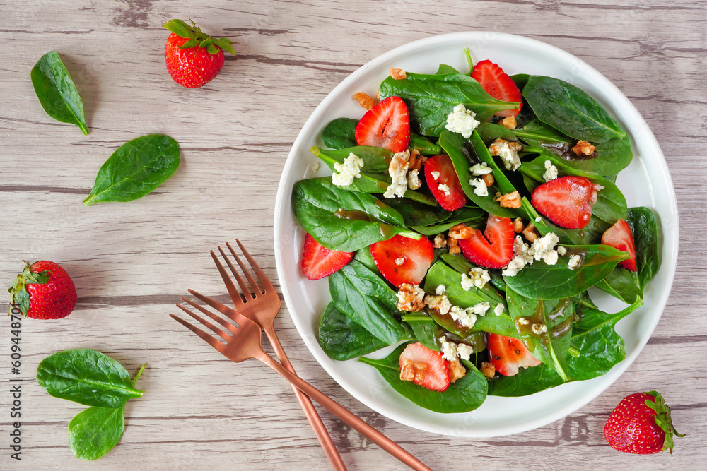 Wall mural Summer salad of spinach, strawberries and blue cheese. Above view table scene on a light wood background. - Wall murals