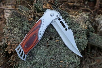 one new iron beautiful hunting modern folding with a brown handle a sharp knife lies on an old...