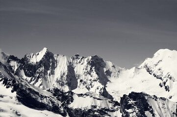 Fototapeta na wymiar Black and white winter snowy mountains in cold sun day