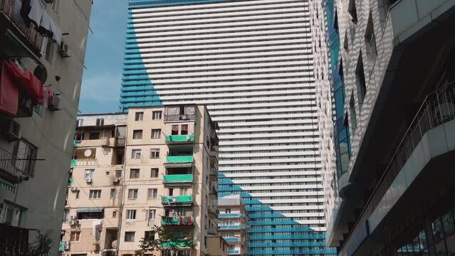 Old District. Facade of old high-rise building in Batumi against background of modern high-rise building or ORBI hotel. Architecture of Batumi. . Shabby walls of house new high-rises. Georgia, Batumi