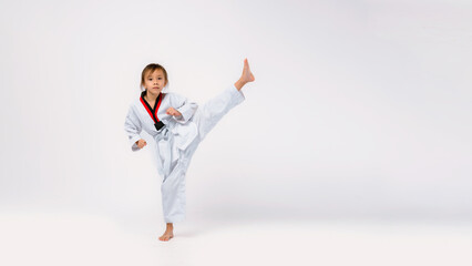 Banner: Asian-Australian girl poses in martial arts Practice taekwondo, karate, judo against a White background in the studio. Asian kids karate or Taekwondo martial arts. Sport kid training action. © VStudio