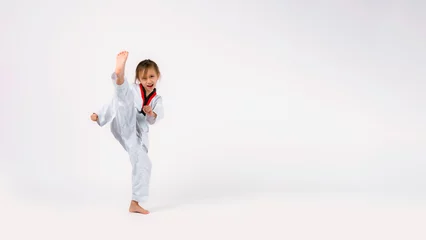 Fotobehang Banner: Asian-Australian girl poses in martial arts Practice taekwondo, karate, judo against a White background in the studio. Asian kids karate or Taekwondo martial arts. Sport kid training action. © VR Studio
