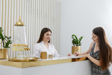 Female receptionist at reception desk with a client in a modern office