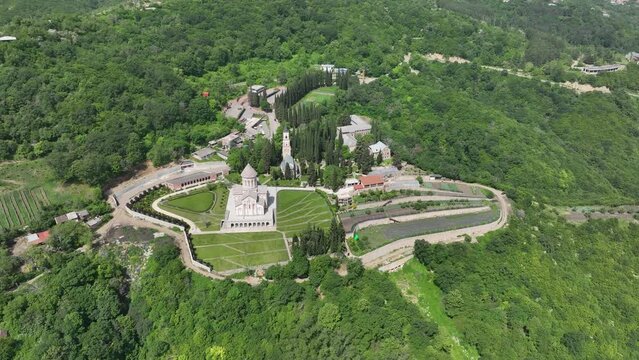 Aerial view of monastic complex of Bodbe nunnery on hillside among tall Cypress trees with Church of St. Nino on sunny day, Sighnaghi, Georgia