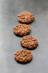 Vegan Chocolate cookies with oatmeal, chocolate chips and hazelnuts. Dark grey background