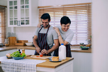 A couple of love preparing meal together with fun happiness and laugh in kitchen at home, boy touching his boyfriend shoulder with love