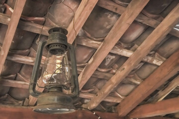 Classic shaped Electric paraffin pressure lamps or kerosene lamp pressure lantern. Old traditional storm lamps attached on javanese joglo limasan house wooden ceilings. Copy text empty blank space.