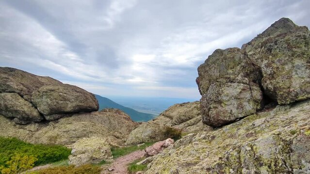Panoramic view of the valley on top of the rocky ridge among the stones overlooking the beautiful valley. Outdoor and mountain hike background. Natural landscape in Bulgaria, Sliven