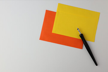 Gelber und orangefarbener Umschlag mit schwarzem Stift auf weißem Hintergrund