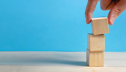 Stack wooden cubes. Human hand stacking blank wooden cube on top of one another.