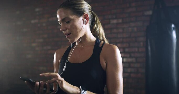 Music, fitness and woman in a gym, relax and workout with wellness, sweat and stress relief. Female person, girl and athlete with earphones, podcast and exercise with smartphone, connect and training