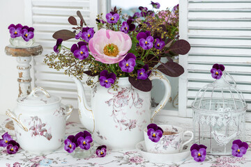 Arrangement mit Blumenstrauß mit pink Pfingstrose und Hornveilchen und vintage Porzellan