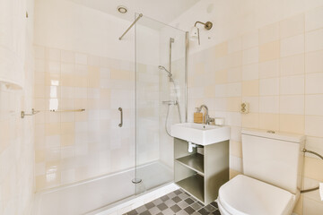 Fototapeta na wymiar a bathroom with a toilet, sink and shower stall in the corner next to it is a checkered tiled floor