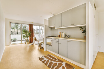 a kitchen and dining area in a house with wood flooring, white walls and light grey cupboards on either side
