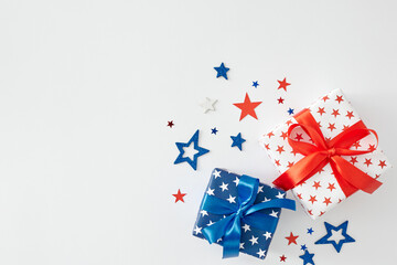 Gifting ideas for American Independence Day. Top view flat lay of gift boxes in national colors, red, blue, white stars on white background with empty space for text or promotional