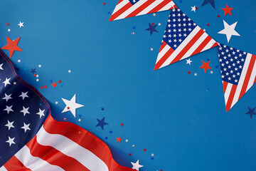 Happy Independence Day of America concept. Top view flat lay of american flag, flag garlands, patriotic party confetti on blue background with empty space for text or ads