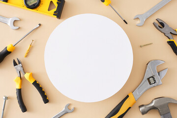 The concept of hand tools for work. Top view flat lay of different set tools on pastel beige background with blank circle for ads or text