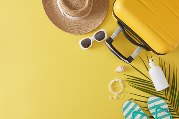 The concept of a seasonal getaway. Top view flat lay of suitcase, sunscreen bottle, beach accessories, palm leaf on yellow background with space for text or branding