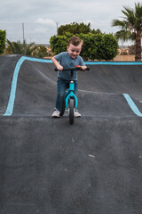 A young child rides the new South Glenmore Park BMX pump track on his bike on a summer evening in...