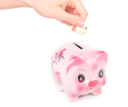 Woman's hand dropping a coin piggy bank