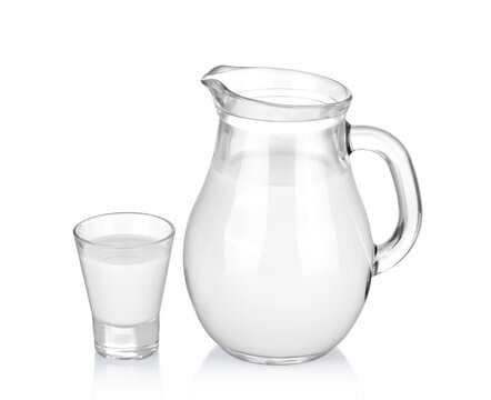A glass of milk and a milk jug on white